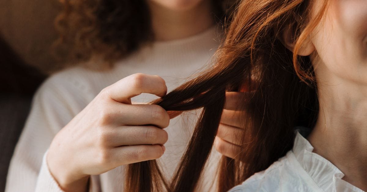 Hands examining strands of long hair