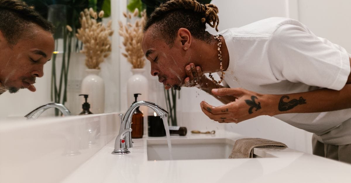 A person splashing water at a bathroom sink