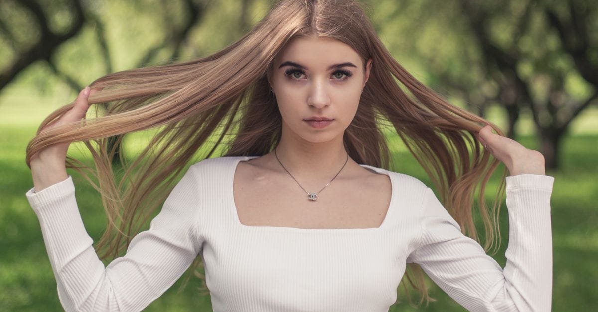 A woman holding out her long healthy hair outdoors