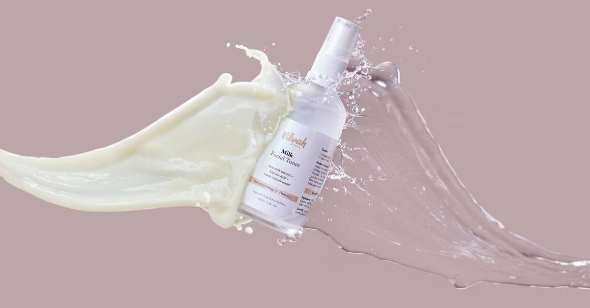 A skincare bottle in a splash of milky liquid
