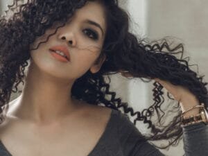 A woman with defined curls running her hands through her hair