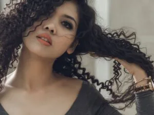 A woman with defined curls running her hands through her hair