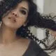A woman with defined curls running her hands through her hair
