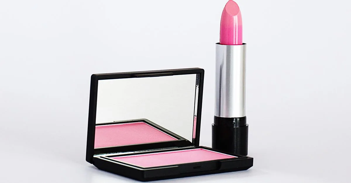 A pink blush compact and lipstick on white
