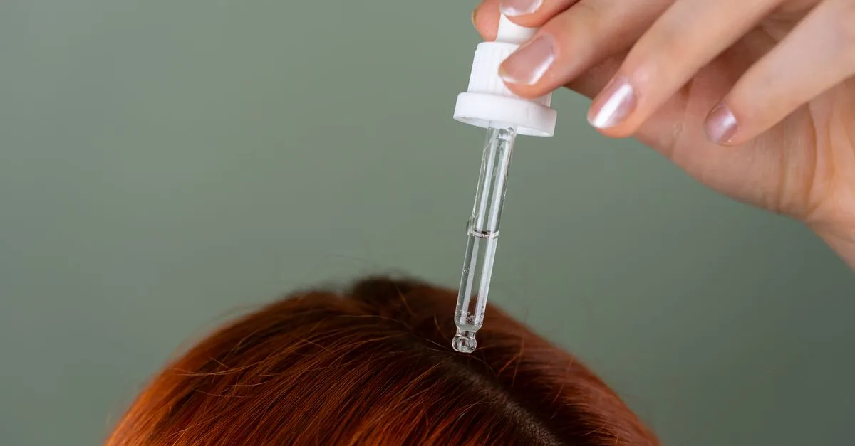 Oil being applied to hair roots with a dropper