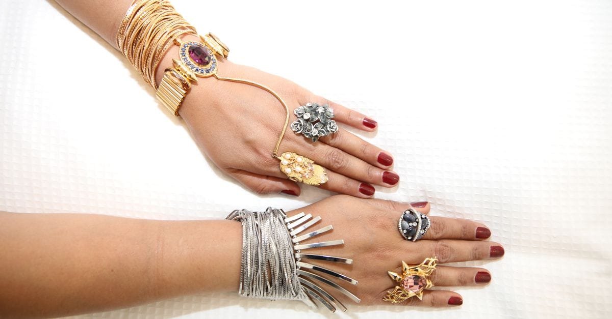 Hands wearing layered gold and silver jewelry