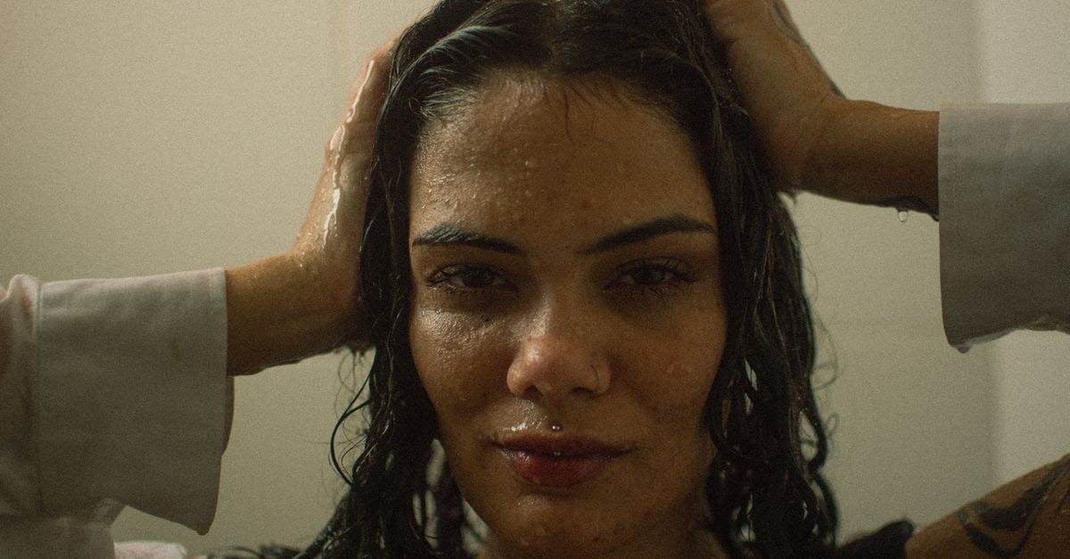 A woman with wet hair, hands at her scalp