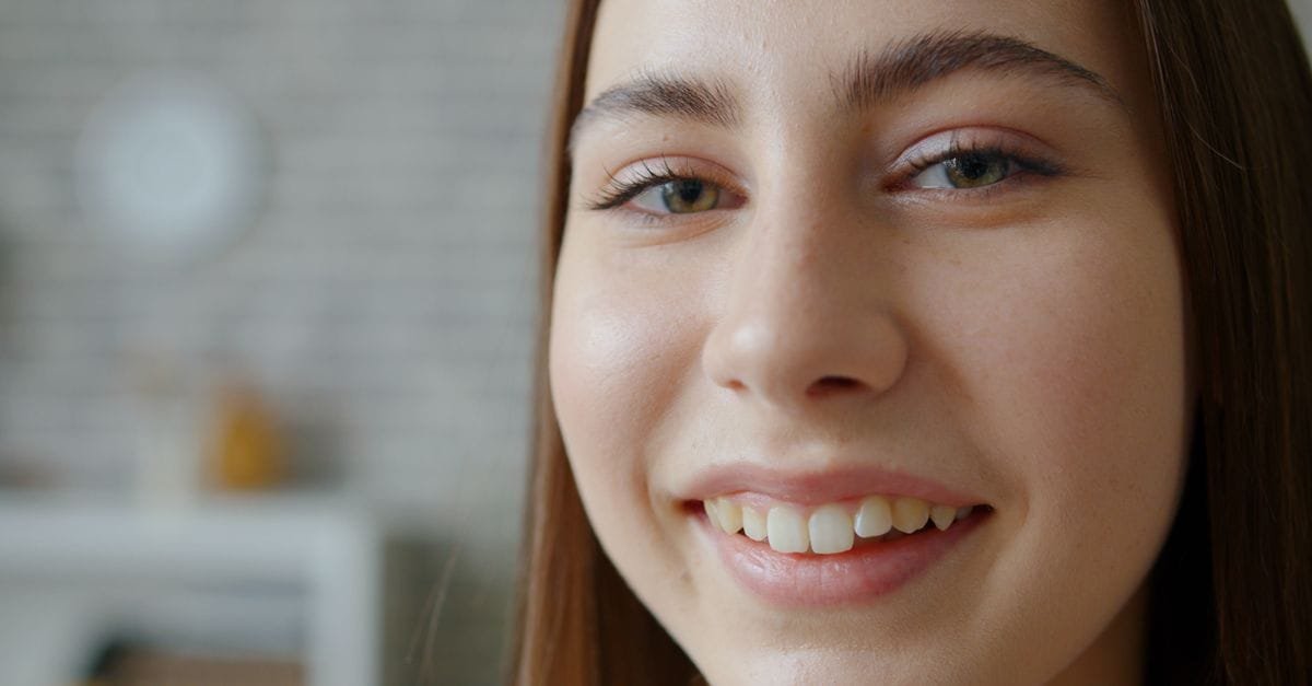 A close-up of a smiling woman with clear skin