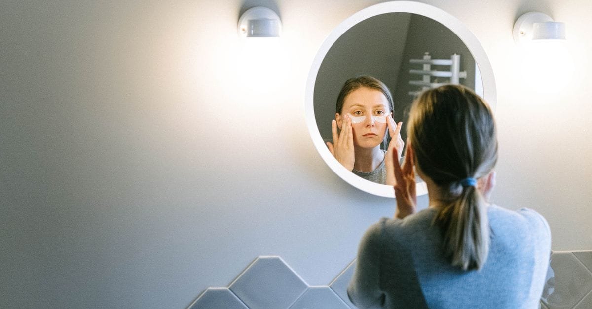 A woman at a round bathroom mirror
