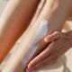A hand smoothing tanning lotion along a leg