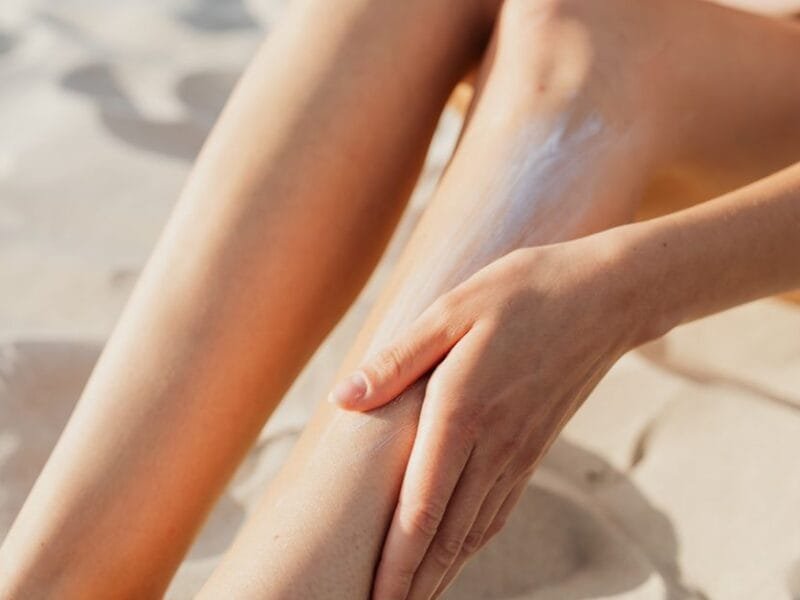 A woman applying lotion to her legs