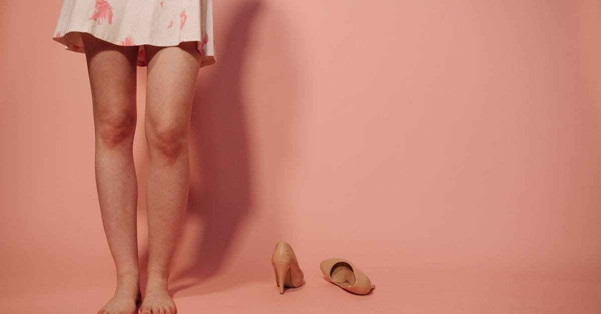 Legs in a summer skirt against a pink background