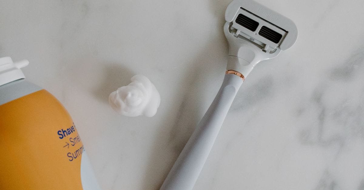 A razor and shaving foam on marble