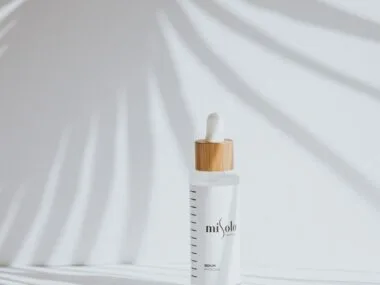 A minimal serum bottle in soft palm-leaf light