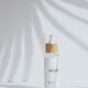 A minimal serum bottle in soft palm-leaf light