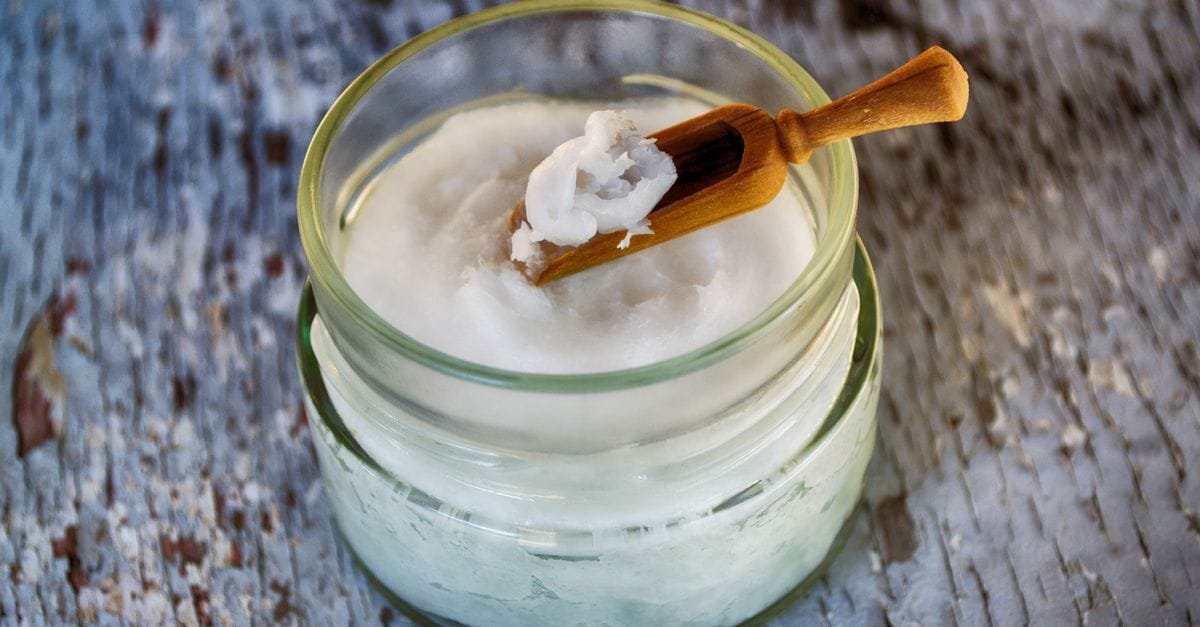 A jar of coconut oil with a wooden spoon