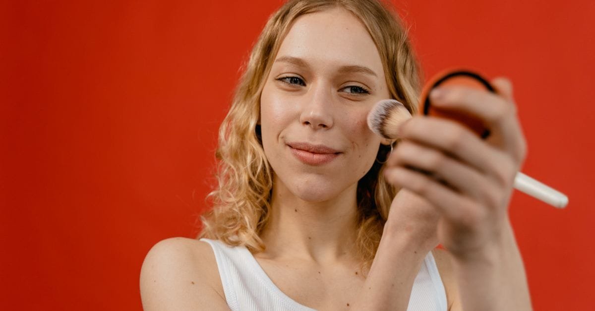 A woman holding a brush and compact