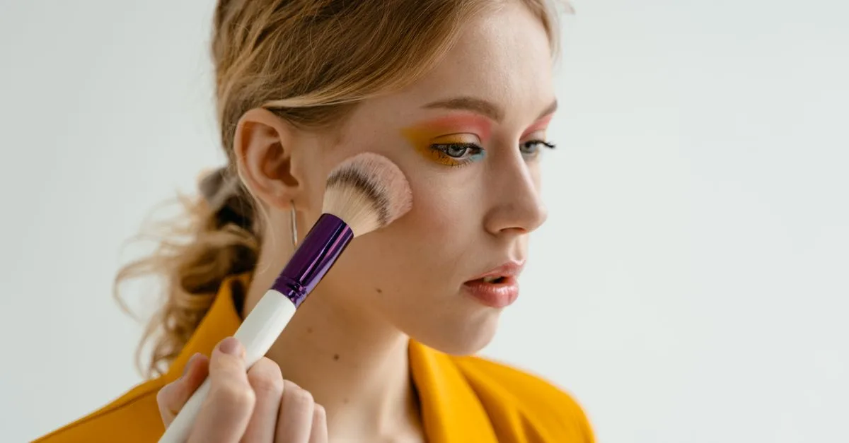 A woman applying blush with a purple brush