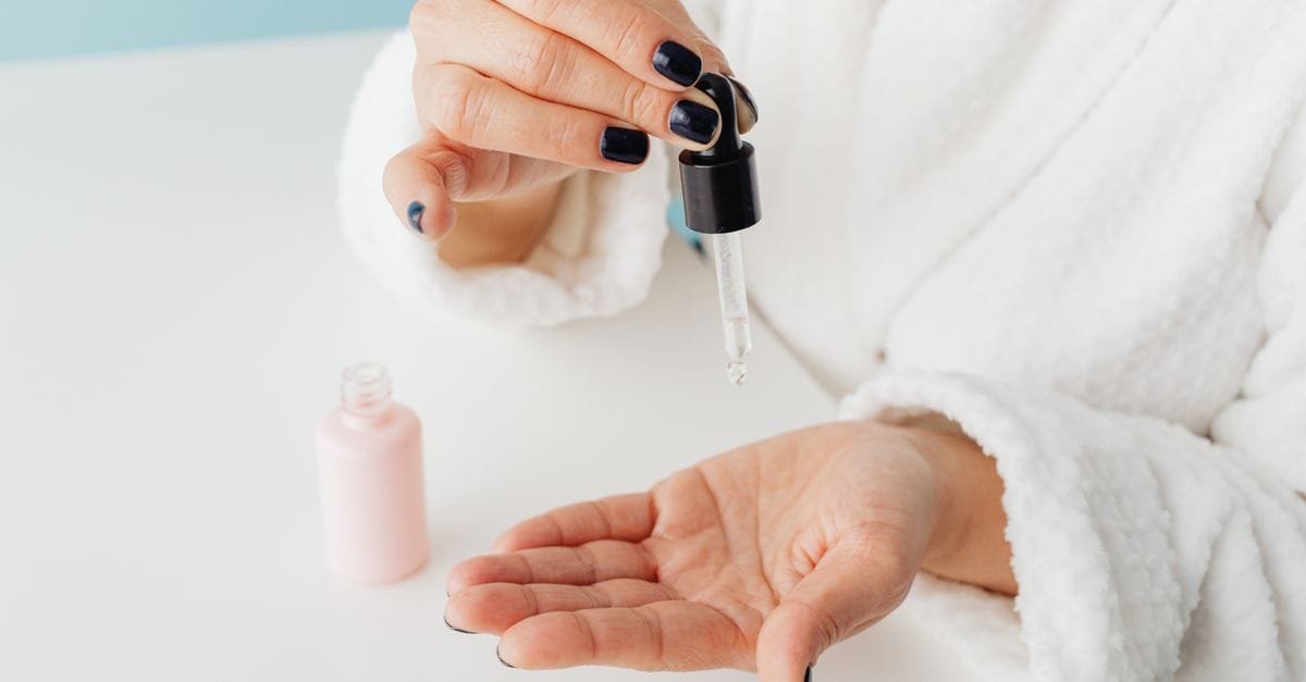 A dropper of serum over an open palm