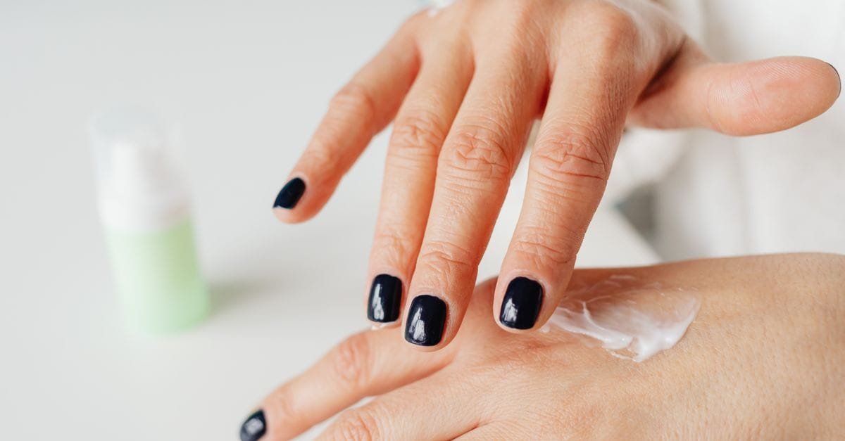 Hand cream applied over painted nails