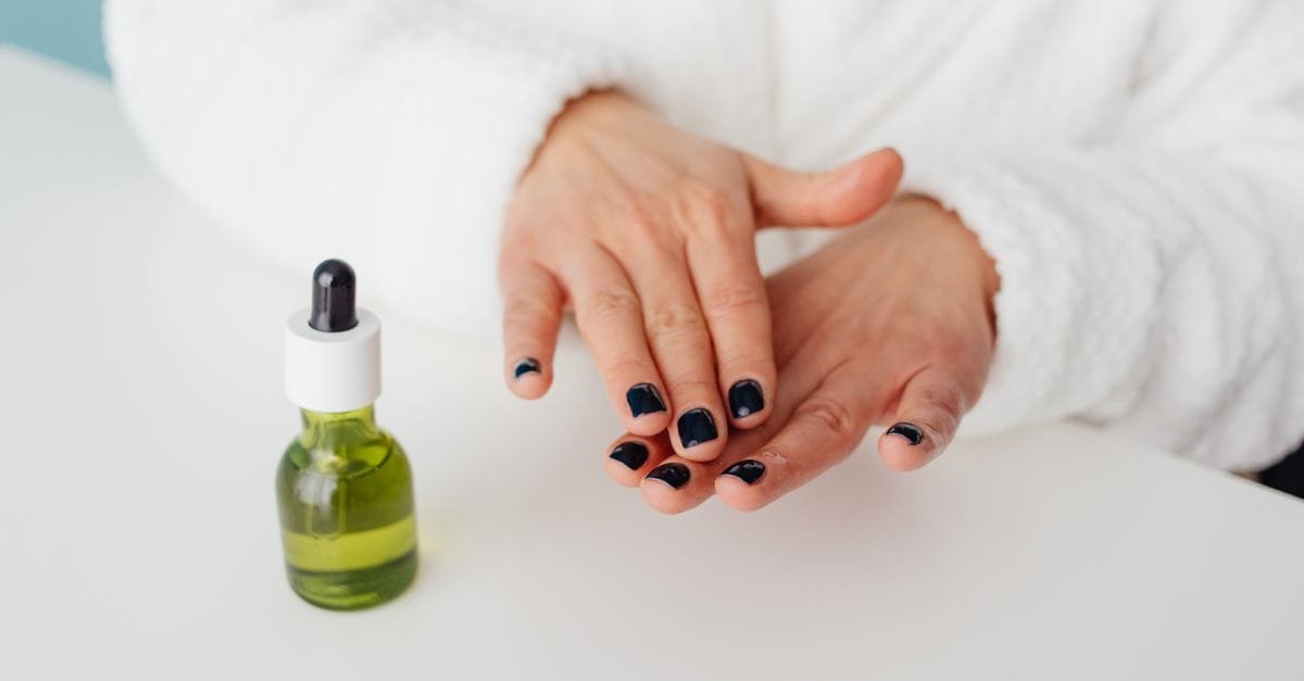 A dropper of oil beside manicured hands