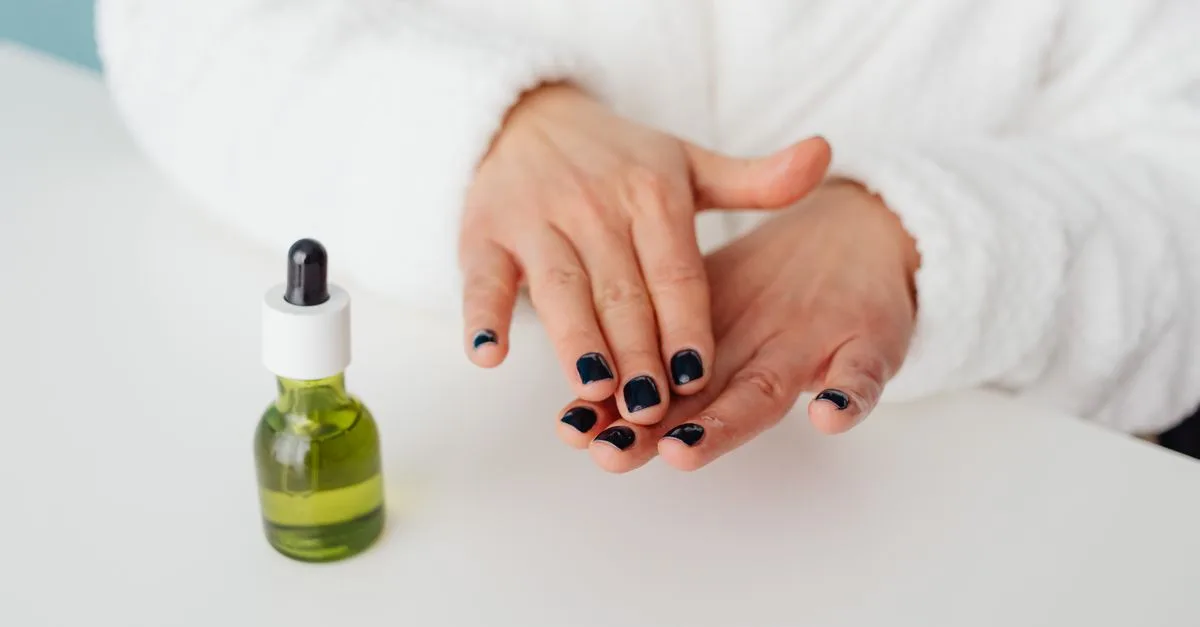 A dropper of oil beside manicured hands
