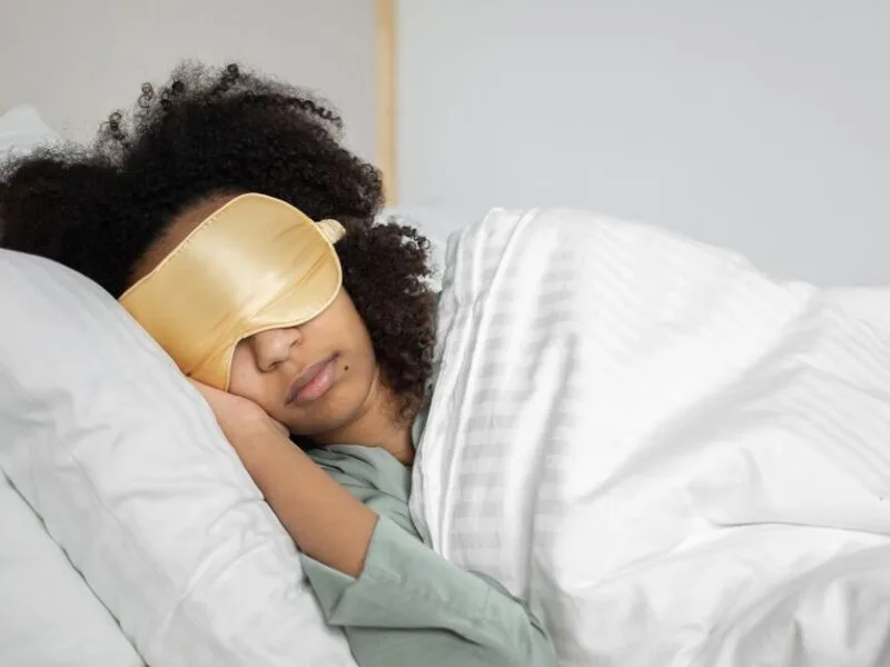 A woman sleeping with a gold silk eye mask
