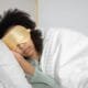 A woman sleeping with a gold silk eye mask
