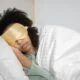 A woman sleeping with a gold silk eye mask