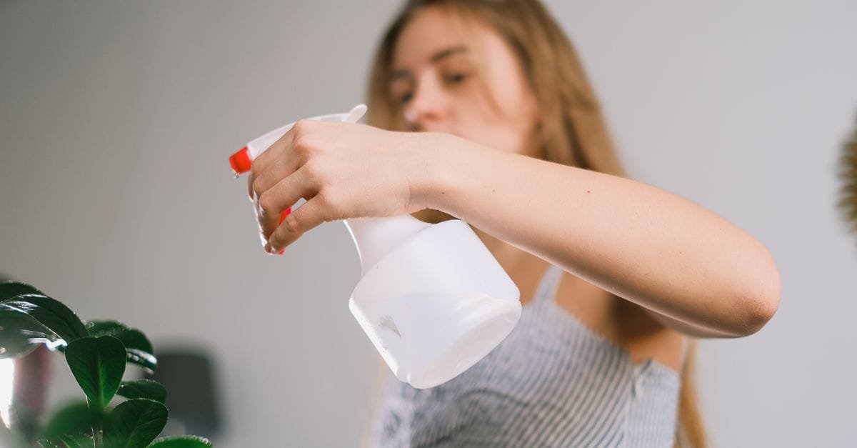 A woman misting her hair with a spray bottle