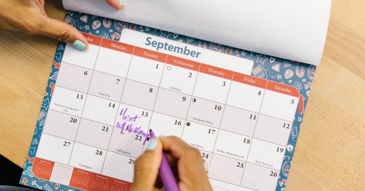 A hand marking dates on a calendar