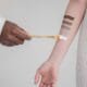A makeup artist swatching foundation shades on a client&rsquo;s arm