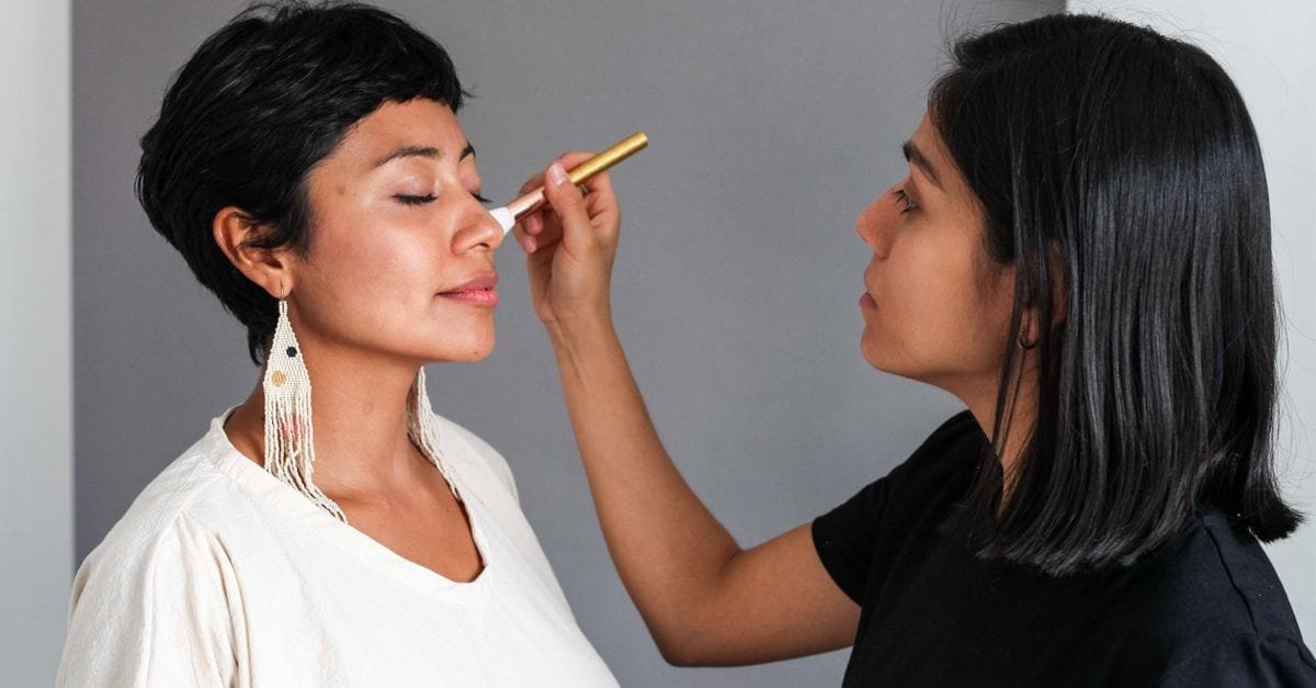 A makeup artist applying blush to a client