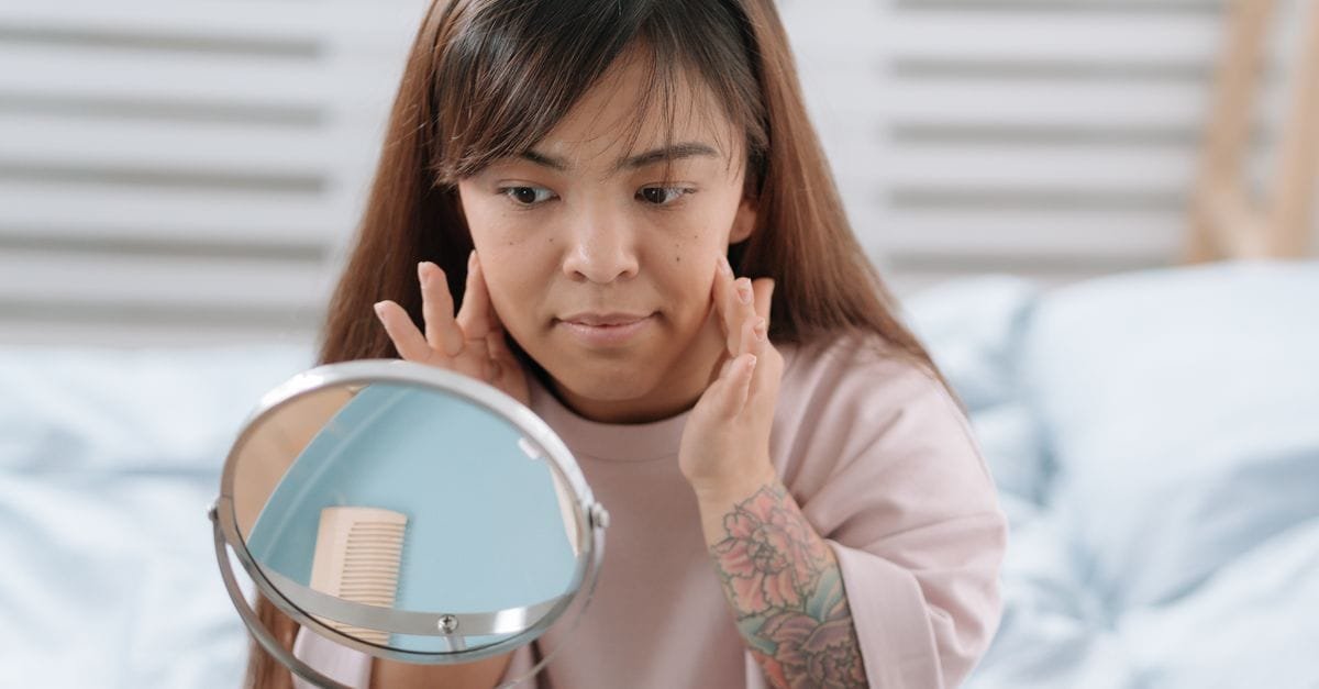 A woman examining her makeup in a round mirror