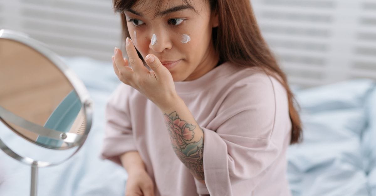 A woman applying treatment at a small mirror