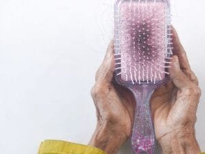 Hands holding a paddle brush filled with buildup