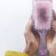 Hands holding a paddle brush filled with buildup