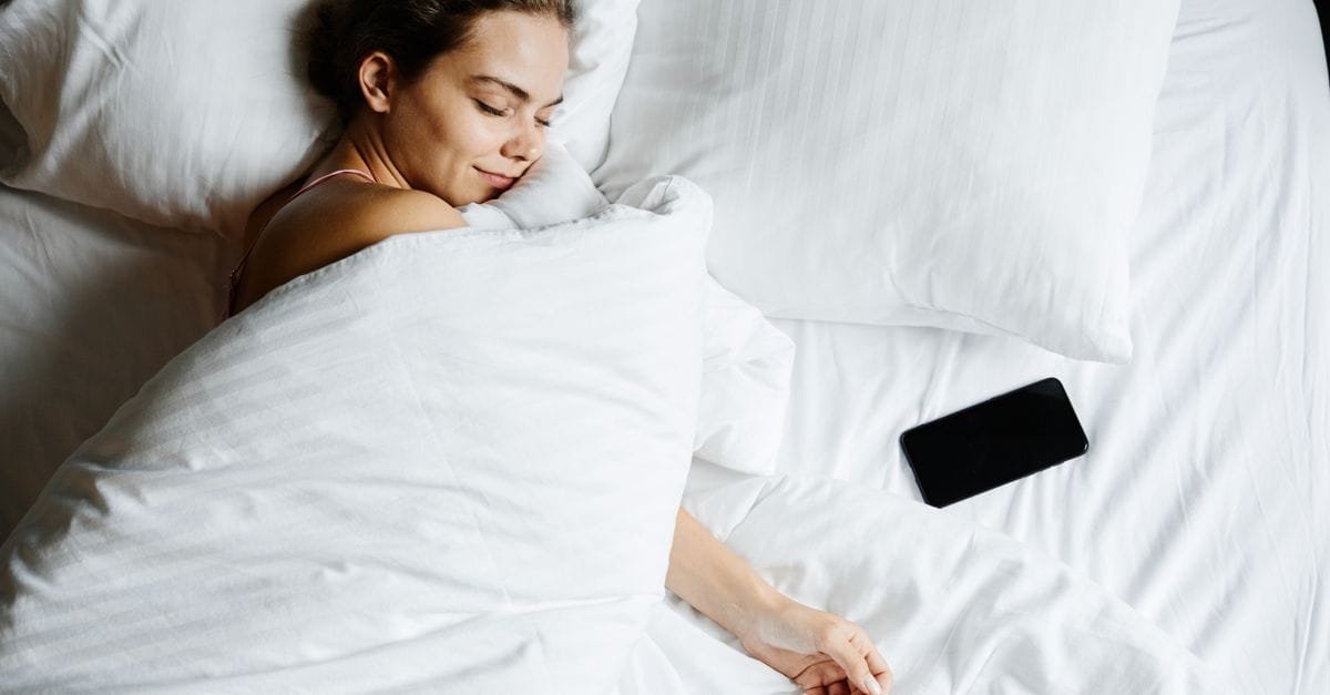 A woman asleep beside her phone
